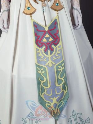 Twilight Princess Zelda cosplay dress centers embroidered teal tabard beneath gold collar above a crest-detailed waist.