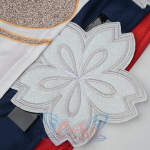 Evanescia cosplay large white glitter sakura applique close-up against white jacket with gold embroidery and navy-red fabric.