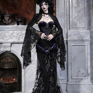Model wearing a gothic black lace mermaid skirt with beaded embroidery, posed near a marble fireplace.