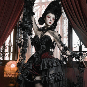 Model in black corset bustier top with red brocade panel, floral ruffled skirt, dramatic gothic headpiece, arm raised.