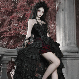 Model seated in gothic black corset bustier top, ruffled skirt, layered necklaces, and dark floral headpiece.
