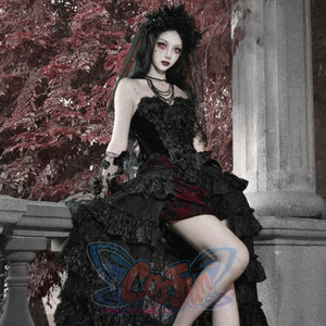 Model seated in gothic black corset bustier top, ruffled skirt, layered necklaces, and dark floral headpiece.