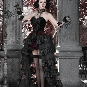 Side view of model in gothic black strapless corset top and ruffled skirt with red brocade, wearing black stockings.