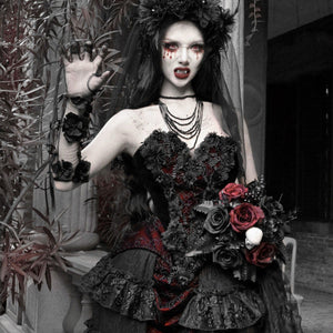 Model in gothic vampire makeup wearing a strapless black and red brocade corset bustier top, holding dark roses.