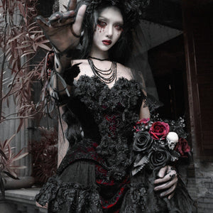 Model in black velvet corset bustier top with red brocade holding a gothic bouquet of black and red roses with skull charm.
