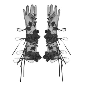 Long black sheer gloves on white background, decorated with 3D floral appliques and ribbon bow details along the length.