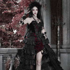 Model in gothic black velvet corset bustier top with red brocade mini skirt, ruffled layers, floral crown, and lace gloves.