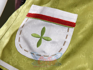 Genshin Impact Yaoyao cosplay pocket centers green cross-stitch design beside red and green ribbon trim on white patch.