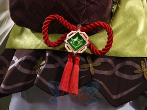 Genshin Impact Yaoyao cosplay sash centers large red cord bow beside gold-framed green emblem and red tassels.