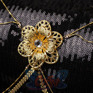 Ornate Mira's costume decoration featuring a gold floral ornament with central gem, connected by multiple gold chains, on black sequined fabric.