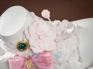 Ruan Mei cosplay costume accessory detail showing pink plum blossom flowers, a green gem brooch, and pink bow ribbon.