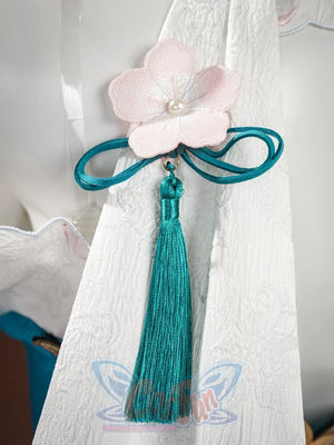 Ruan Mei cosplay costume detail with pink plum blossom on white sleeve, teal Chinese knot clasp, and teal tassel.
