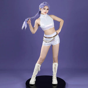 The cosplay features a white, sleeveless, high - neck crop top paired with matching white shorts, accented by a gold chain belt. White lace - up boots complete the Rumi - inspired look against a purple backdrop.