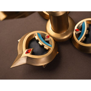 Sandrone cosplay costume back ornament macro detail showing gold crescent elements with teal inlay and red diamond gem accents