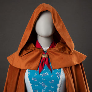Holly cosplay yellow-brown hooded cloak close-up with red bow and blue floral dress visible underneath