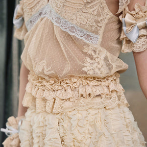 Close-up of the camisole ruffled hem, sheer dotted mesh, and cream lace texture