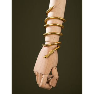 Worn view of Charlie Morningstar snake arm cuff with gold coiled shape, black eyes and wrapped bracelet form
