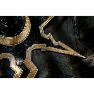 Honkai Star Rail Khaslana cosplay gold emblem close-up shows angular trim on glossy black fabric