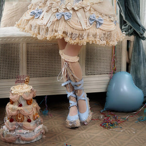 cropped front styling view of a cream Rococo Lolita lace cake skirt with blue bow accents