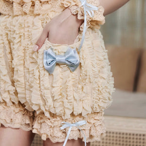 Close-up of pale blue satin bow, cream lace trim, and ruffled fabric texture