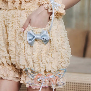 Close-up of the pumpkin bloomers pale blue satin bow, cream lace trim, and ruffled fabric texture