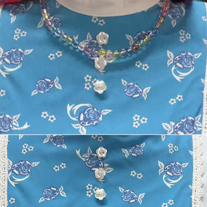 Close-up of Holly cosplay dress fabric with rose pattern and beaded necklace
