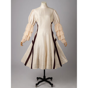 Violet Evergarden cosplay costume pairs a striped dress with gathered ruffle sleeve layers and dark vertical paneling.