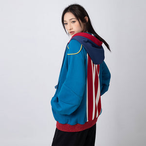 Woman wearing blue and red striped Homelander cosplay jacket with hood, side view