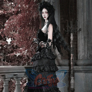 Model in all-black gothic velvet corset bustier top with ruffled tiered skirt, floral headpiece, and black rose in hand.