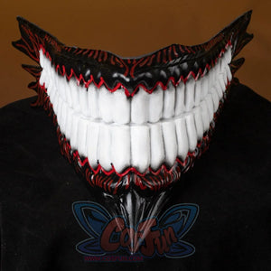 A tight close-up zooms on the Body Party helmet’s mouth—large white teeth, red detailing, and a sharp downward tip—poised on a dark surface.
