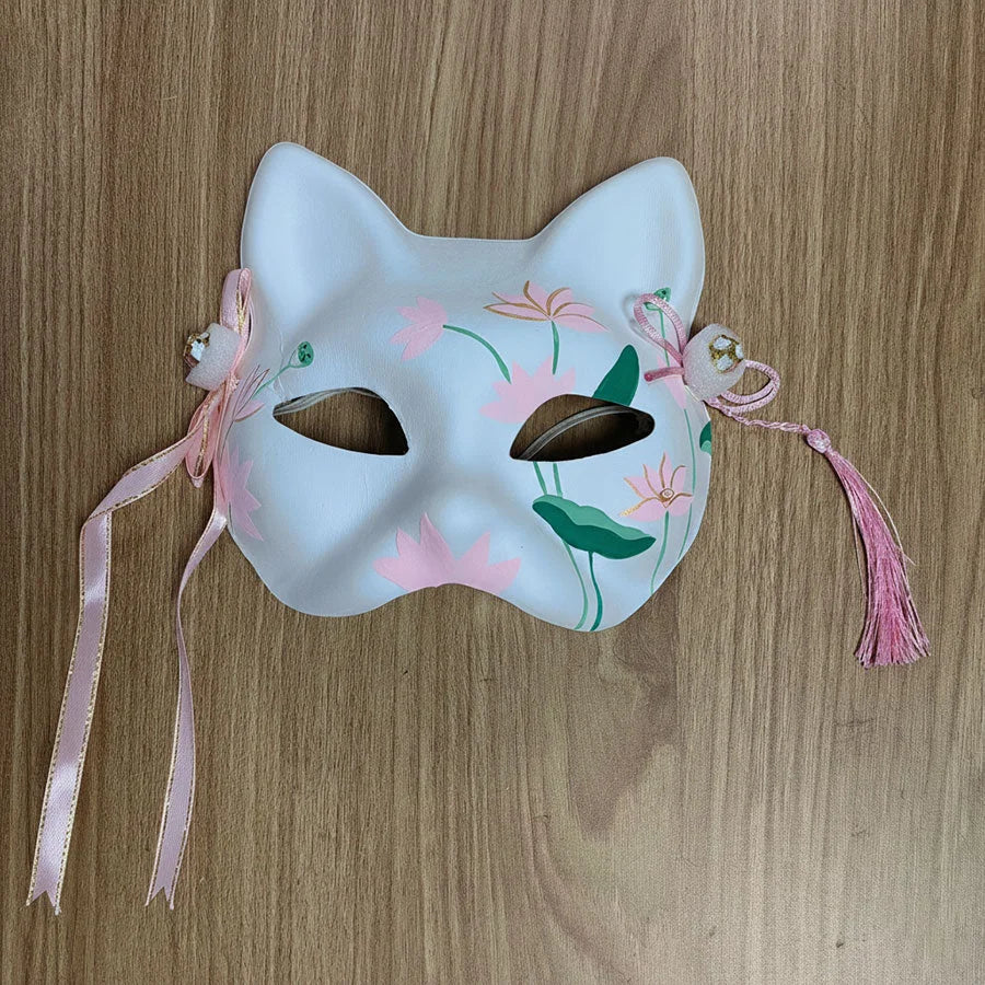 Cat-shaped mask with floral designs and pink ribbons on a wooden surface