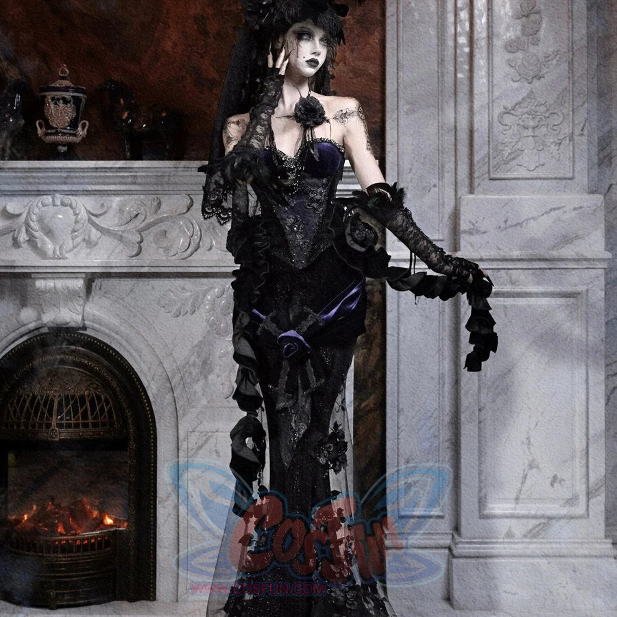Model wearing a gothic black lace mermaid skirt and feathered hat, shown in a three-quarter pose by a fireplace.
