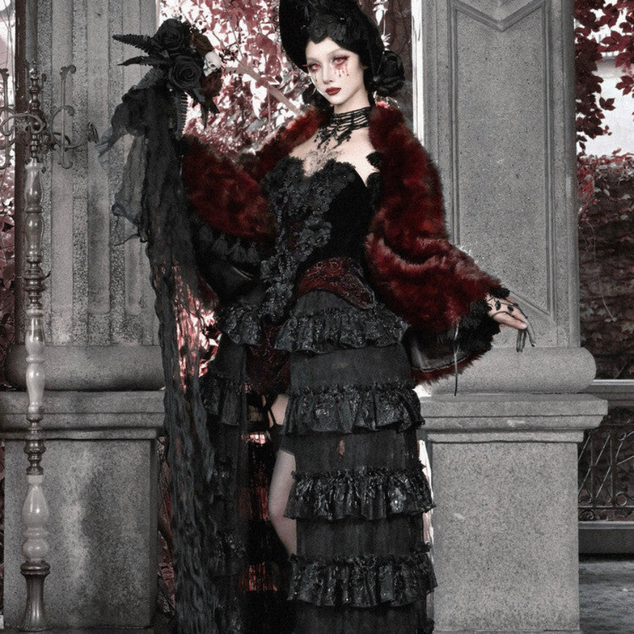 Model in black gothic velvet corset bustier top and tiered skirt, draped with a red faux fur wrap and black rose headpiece.