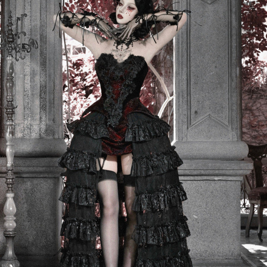Model with arms raised in gothic black corset bustier top, red brocade, tiered ruffled skirt, and garter stockings.