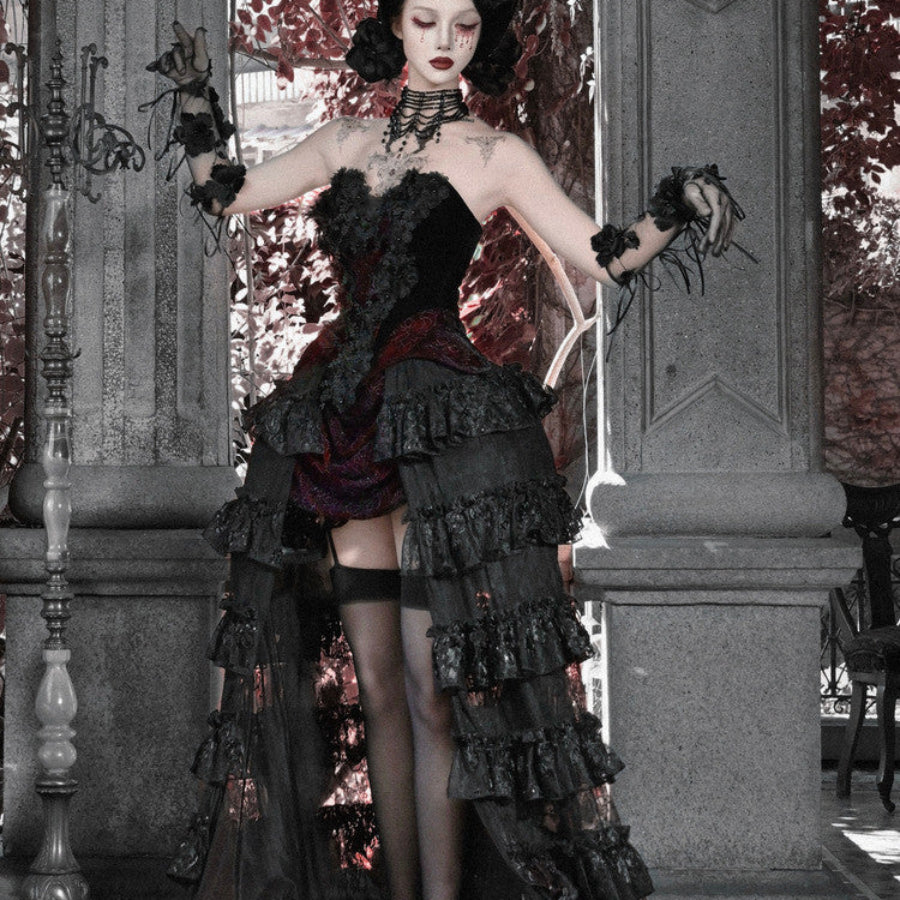 Side view of model in gothic black strapless corset top and ruffled skirt with red brocade, wearing black stockings.