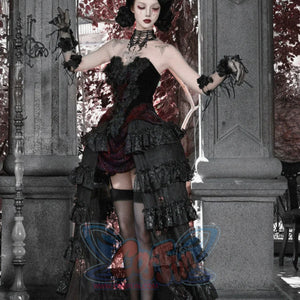 Side view of model in gothic black strapless corset top and ruffled skirt with red brocade, wearing black stockings.