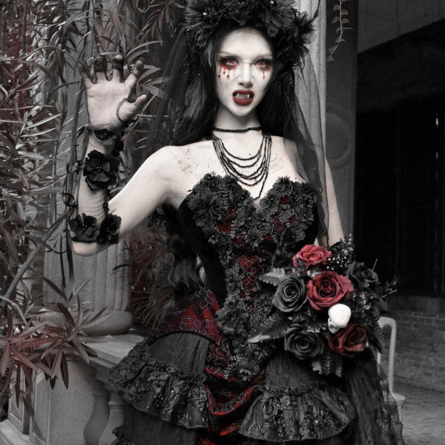 Model in gothic vampire makeup wearing a strapless black and red brocade corset bustier top, holding dark roses.
