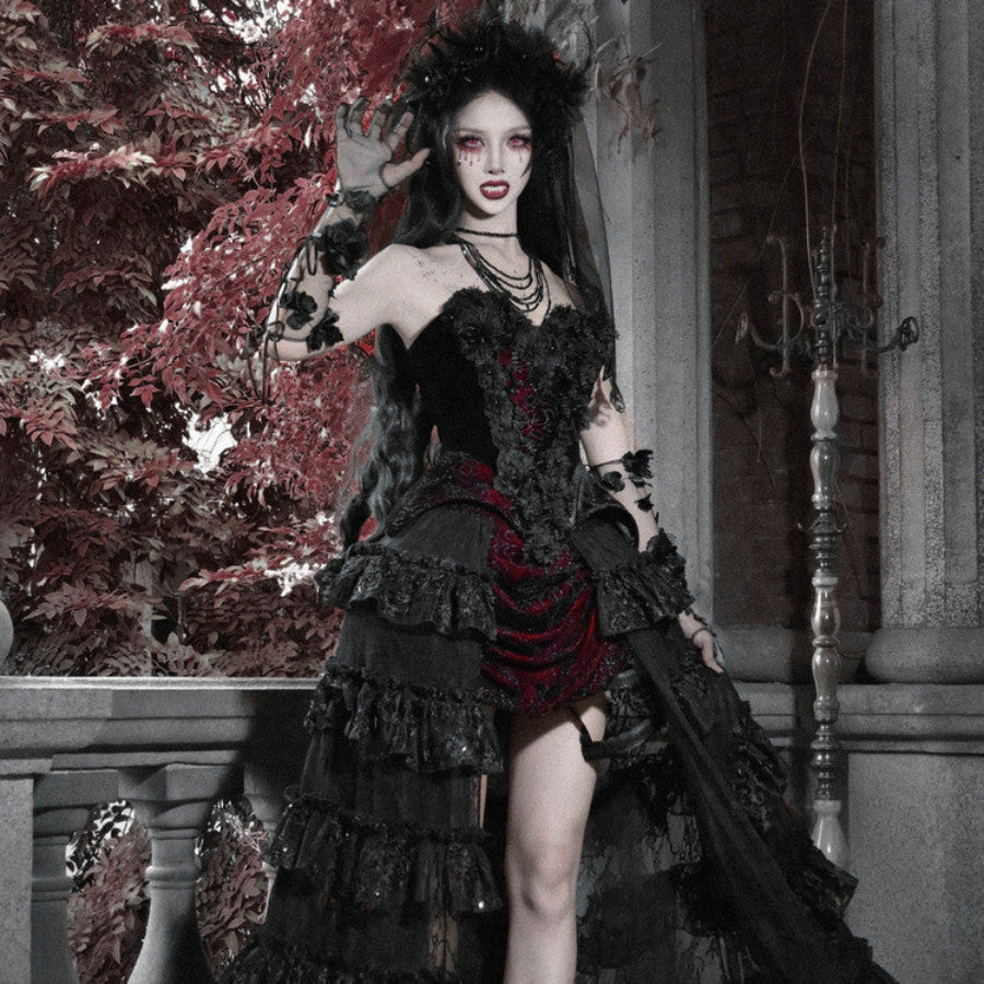 Model in gothic black velvet corset bustier top with red brocade mini skirt, ruffled layers, floral crown, and lace gloves.