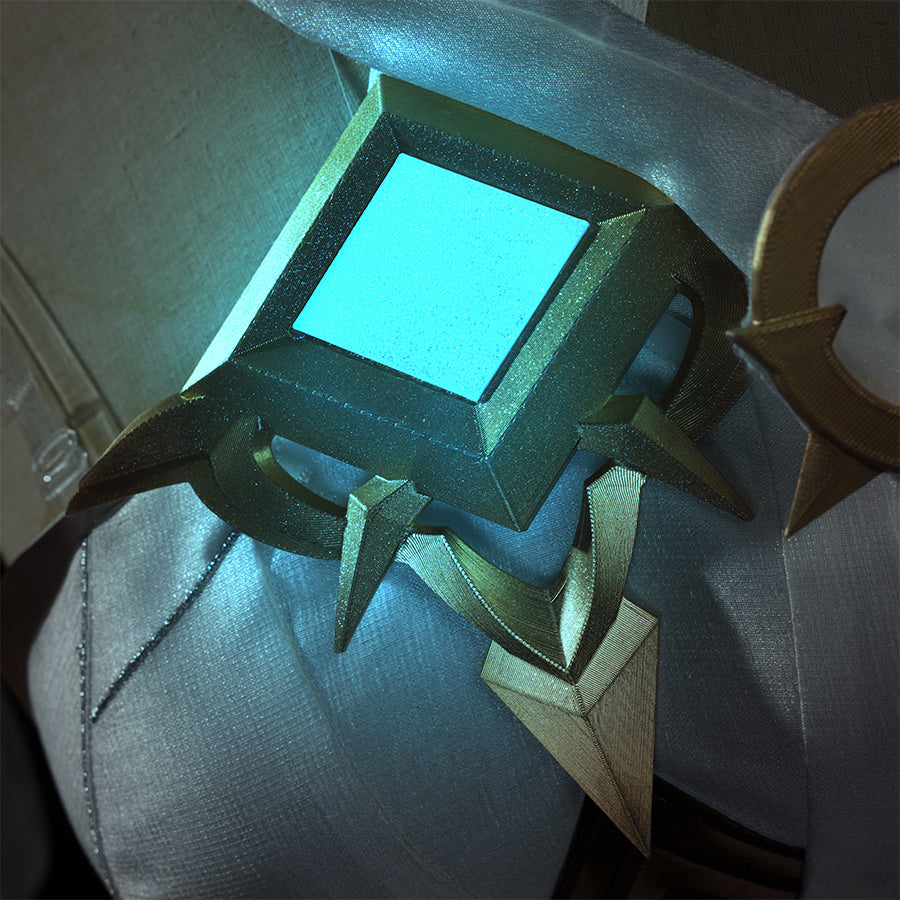 Lumine cosplay dark costume chest armor detail with glowing blue square gem in gold frame
