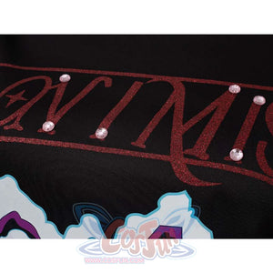 Close - up of red glittery text with pink gems on Mira’s black cosplay top.