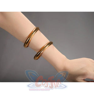 Robin cosplay accessory close-up showing two gold bangles worn on a wrist against a gray background