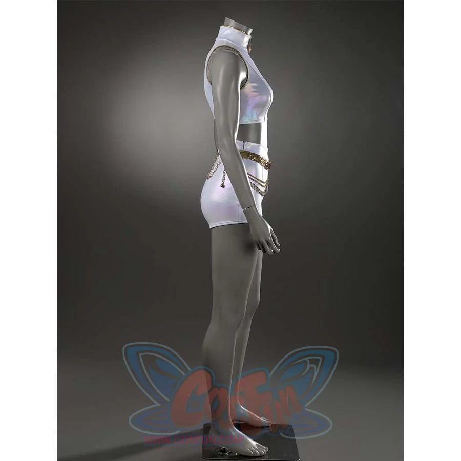 Angled view of the white stage set, emphasizing the iridescent fabric of the high - neck top and shorts, along with the decorative gold belt. 