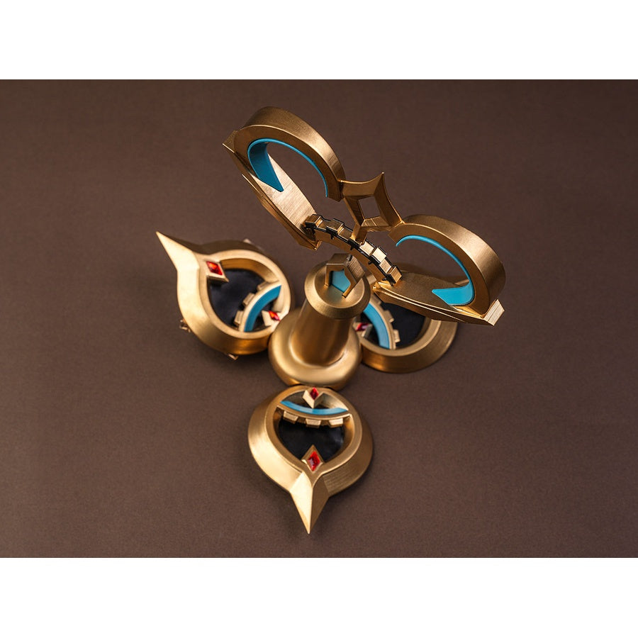 Sandrone cosplay costume back ornament flat lay showing gold piece with teal crescent inlays, red gems, and bell-shaped center