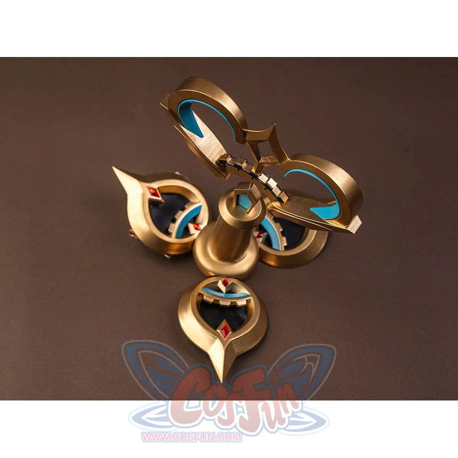 Sandrone cosplay costume back ornament flat lay showing gold piece with teal crescent inlays, red gems, and bell-shaped center