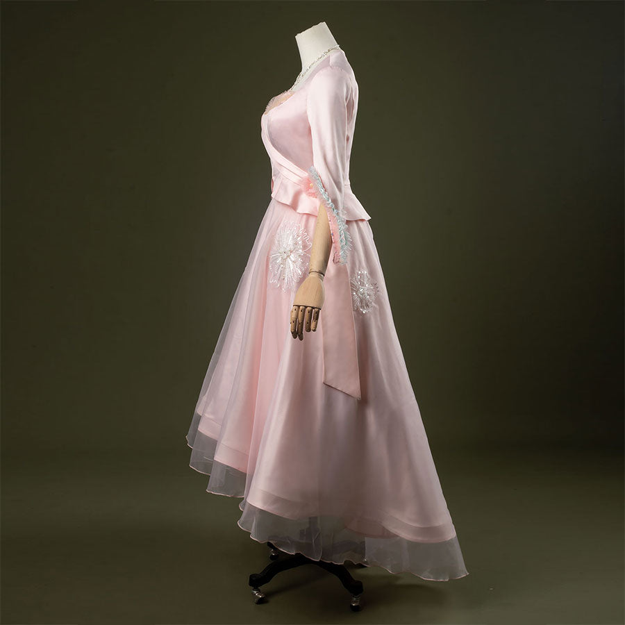 Glinda cosplay costume set featuring pastel pink vintage-inspired gown, ruffled lace cuffs, lace-trimmed sweetheart top, tulle overlay skirt, and necklace. Front and side views.