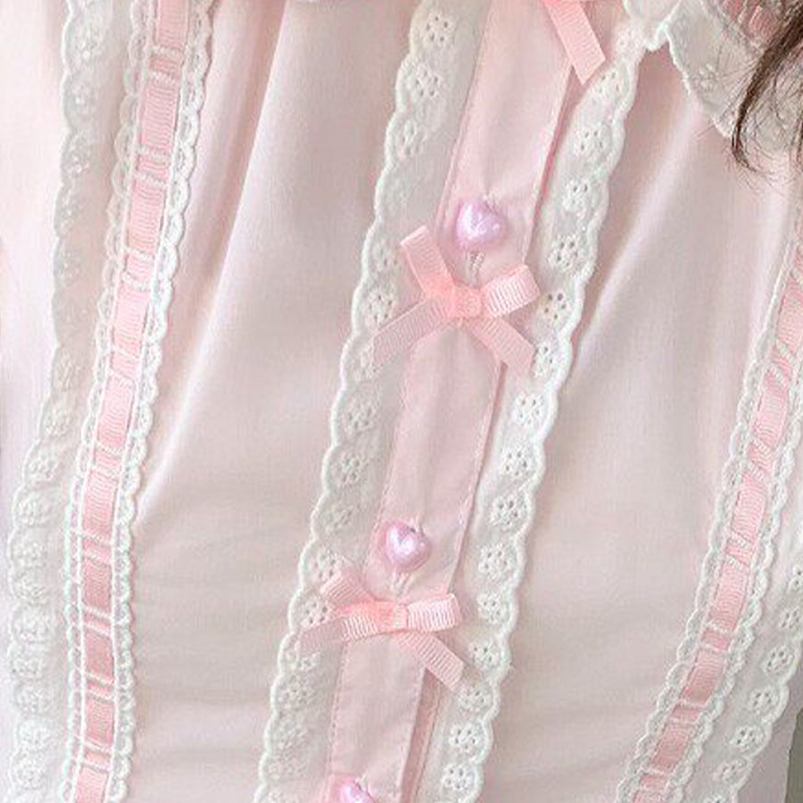 Close-up of pink Lolita blouse placket featuring white lace trim, pink satin ribbon, and heart pearl buttons.
