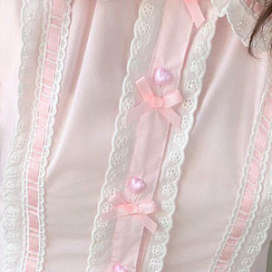 Close-up of pink Lolita blouse placket featuring white lace trim, pink satin ribbon, and heart pearl buttons.