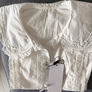 Flat lay of white Lolita blouse highlighting the wide lace-edged Peter Pan collar and eyelet lace front placket.