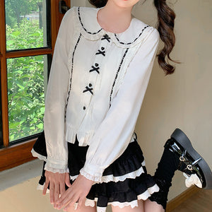 White-black Lolita blouse with black-trimmed Peter Pan collar, black heart buttons with bow decoration, and ruffled lace cuffs, full figure view.