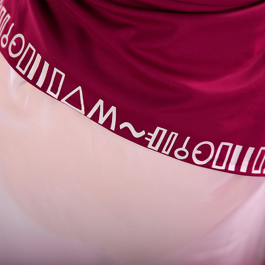 Close-up of Hylian script detail on the hem of the Princess Zelda cosplay tankini top, showing white symbolic print on wine-red fabric.